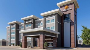 A modern hotel with a prominent 'La Quinta' sign, featuring a multi-story structure with a flat roof and a covered entrance area. - La Quinta Inn & Suites by Wyndham Durant (Durant)