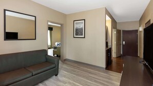 A modern living room with a sofa, a flat-screen TV, and a framed picture on the wall. - La Quinta Inn & Suites by Wyndham Durant (Durant)