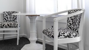 A corner room with two white chairs with black and white patterned upholstery, a white table, and a black and white pendant lamp. - Solé Beach (Montauk)