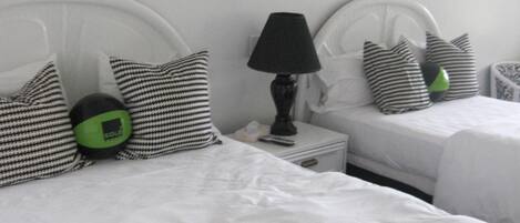 Two single beds with white headboards, a black lamp on a bedside table, and striped pillows.