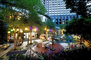 An outdoor dining area with tables and chairs, surrounded by trees and illuminated by string lights. - Crowne Plaza Chengdu West by IHG (Chengdu)