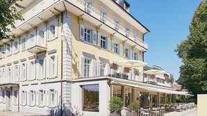 A multi-story building with balconies and outdoor seating, located in a sunny urban setting. - Hotel Schützen (Rheinfelden)