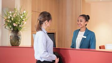 A reception area with a wooden panel wall, a vase of flowers, and a red reception desk.