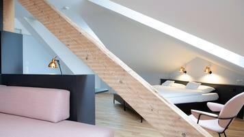 Un dormitorio tipo loft moderno con techo inclinado, una cama, un escritorio y dos sillas.