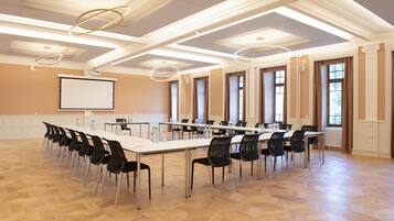 A conference room with a long table, chairs, a projector screen, and a large window.