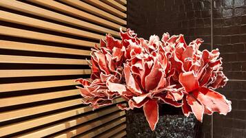 A potted plant with red foliage in front of a wooden slatted wall.