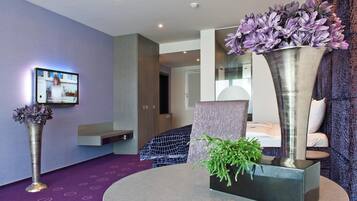 Une chambre d’hôtel moderne dotée d’un grand lit, d’un coin salon et d’un téléviseur fixé au mur.