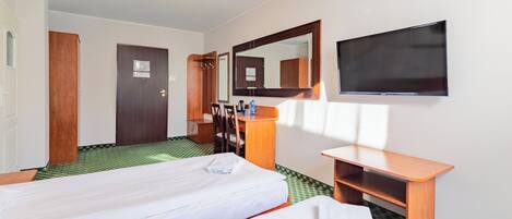 A hotel room with two beds, a desk, a chair, a mirror, and a TV.