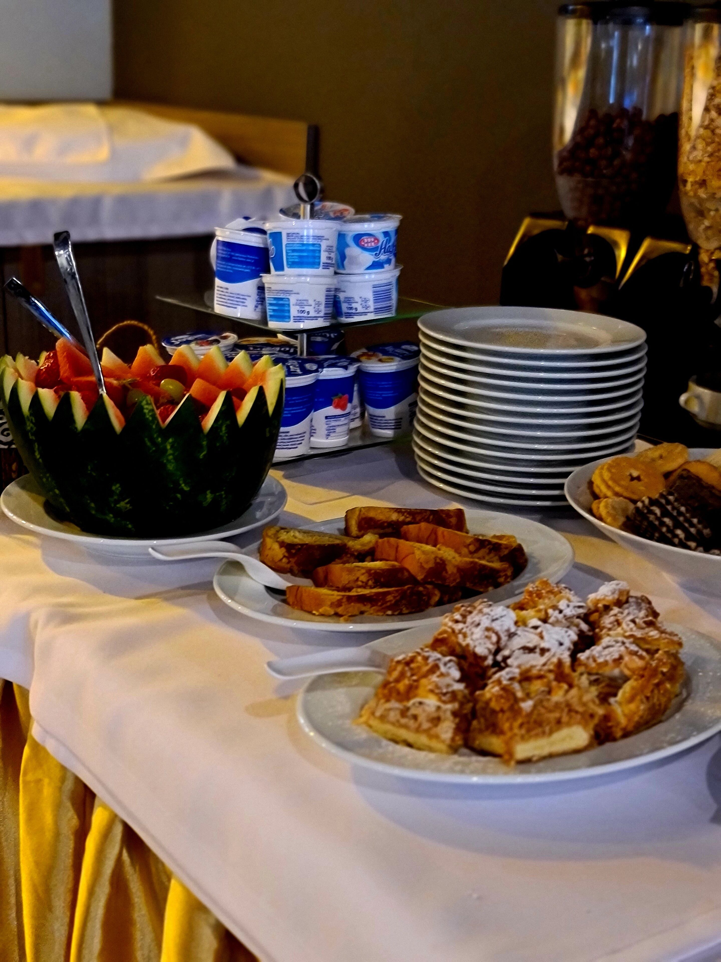 A buffet table with various food items including fruit, yogurt, and pastries.