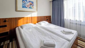Una habitación de hotel con dos camas, un cuadro en la pared y una ventana con cortinas.