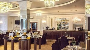 Un comedor amplio con techos altos, candelabros y una barra.