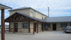 A building with a covered entrance and a parking area. - Winterton Suites (Williston)