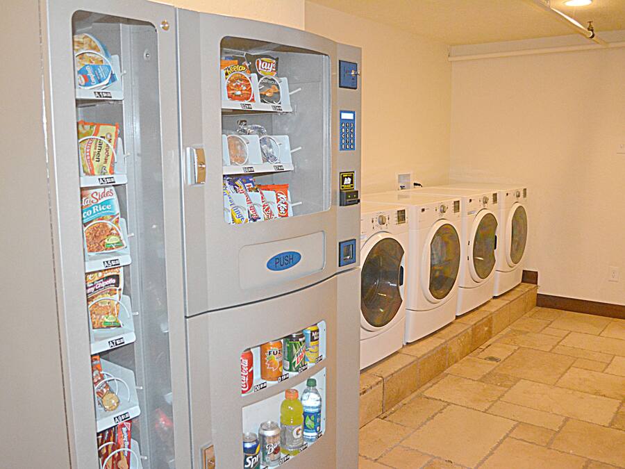 A laundry facility with vending machines and a row of front-loading washers.