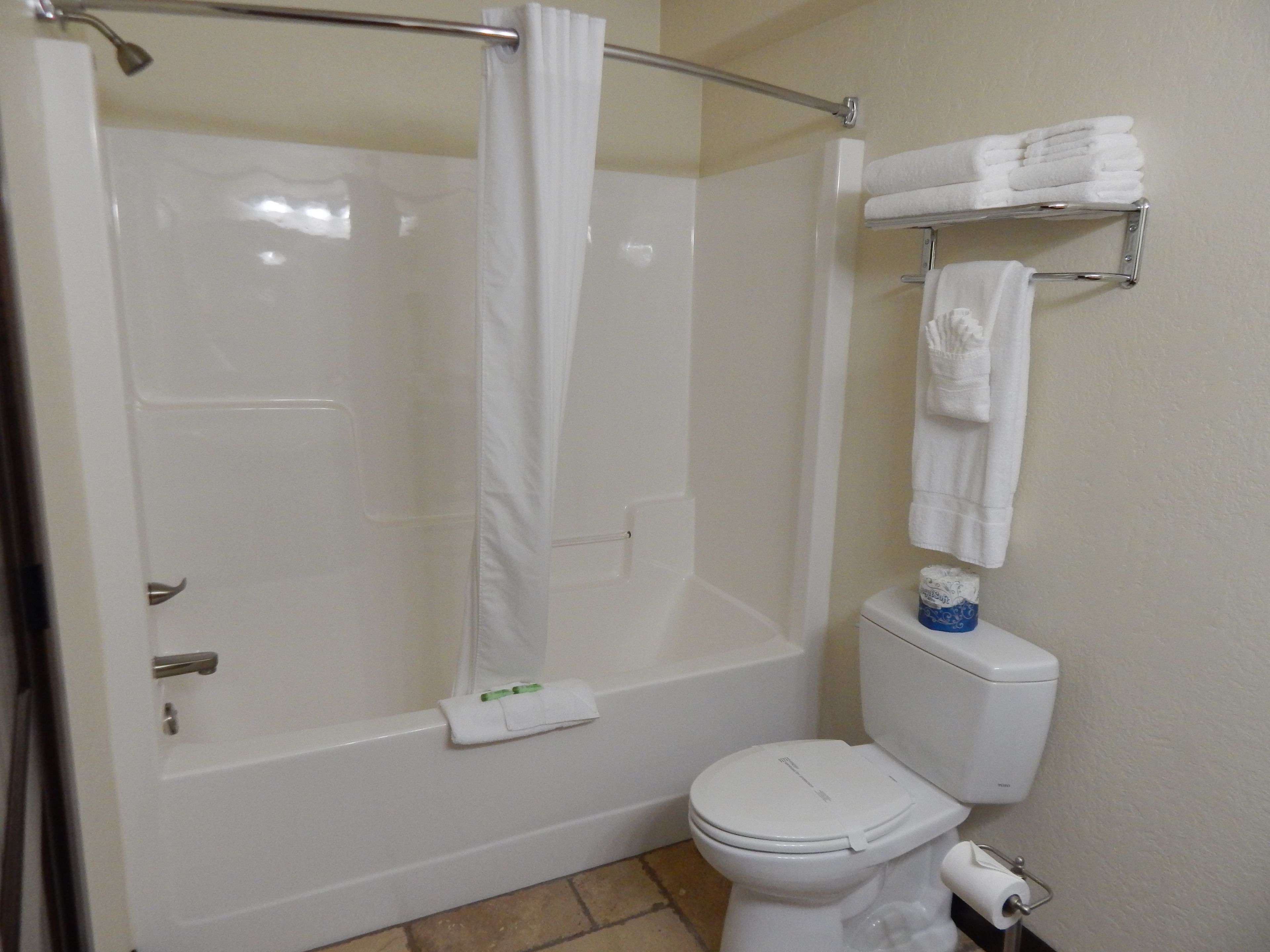 Un baño con ducha, inodoro y toallero.