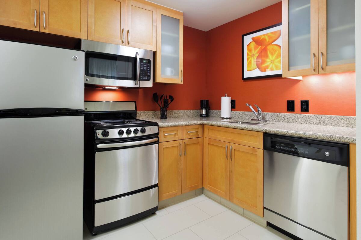 A kitchen with stainless steel appliances, wooden cabinets, and a granite countertop.
