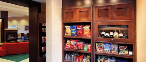 A snack display in a hotel lobby with various chips, snacks, and bottled beverages.