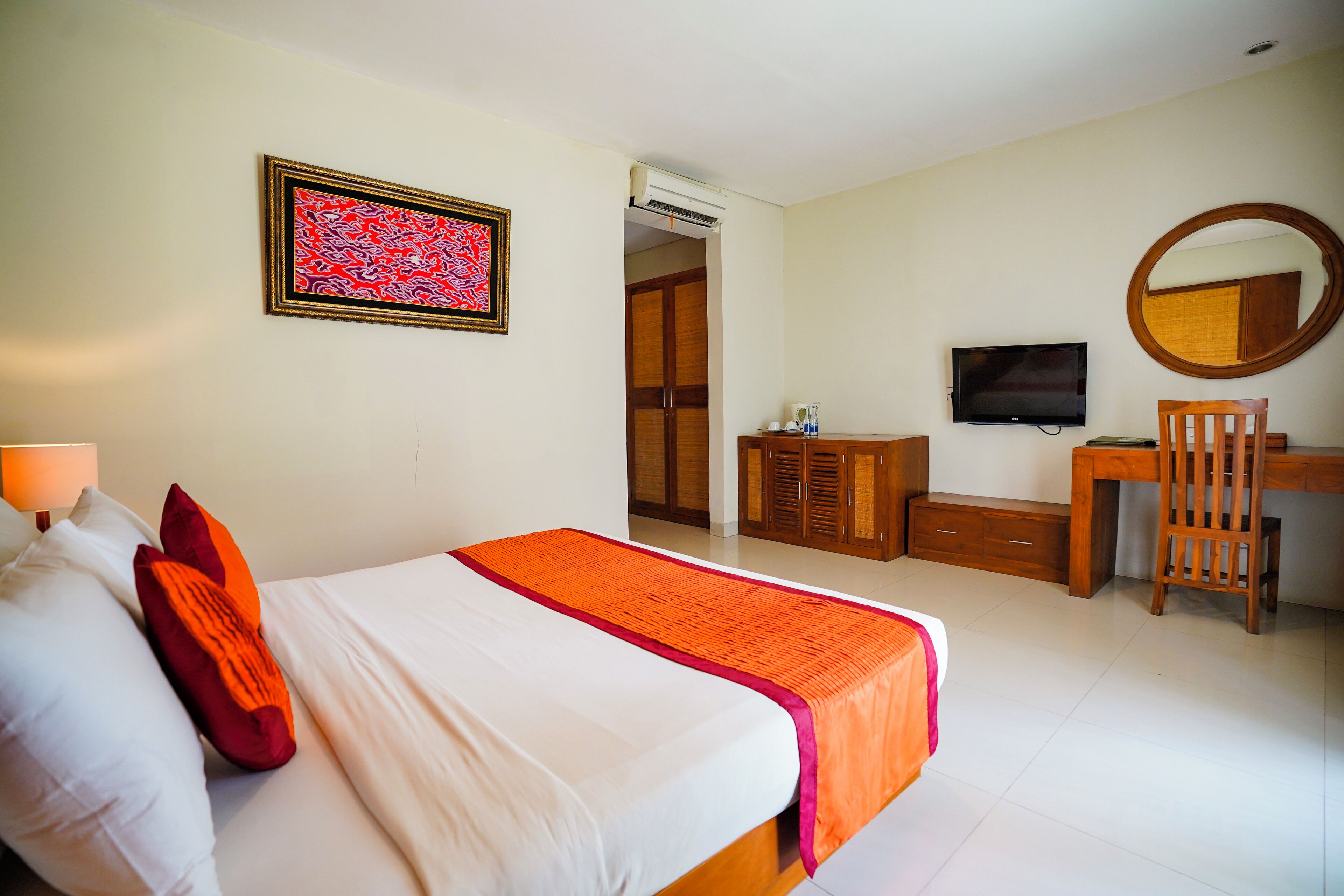A hotel room with a bed, a desk, a chair, a television, and a wardrobe.