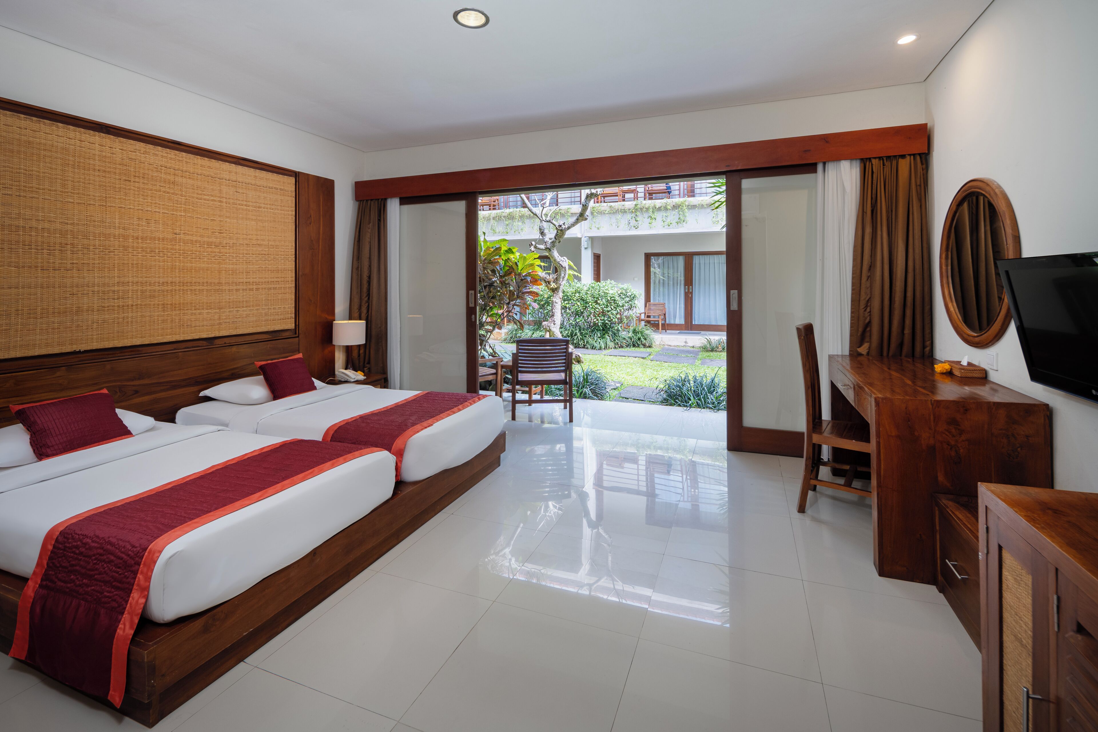 A hotel room with two beds, a desk, a chair, and a TV.