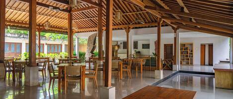 A spacious indoor area with wooden tables and chairs, a polished floor, and a high ceiling with exposed beams.