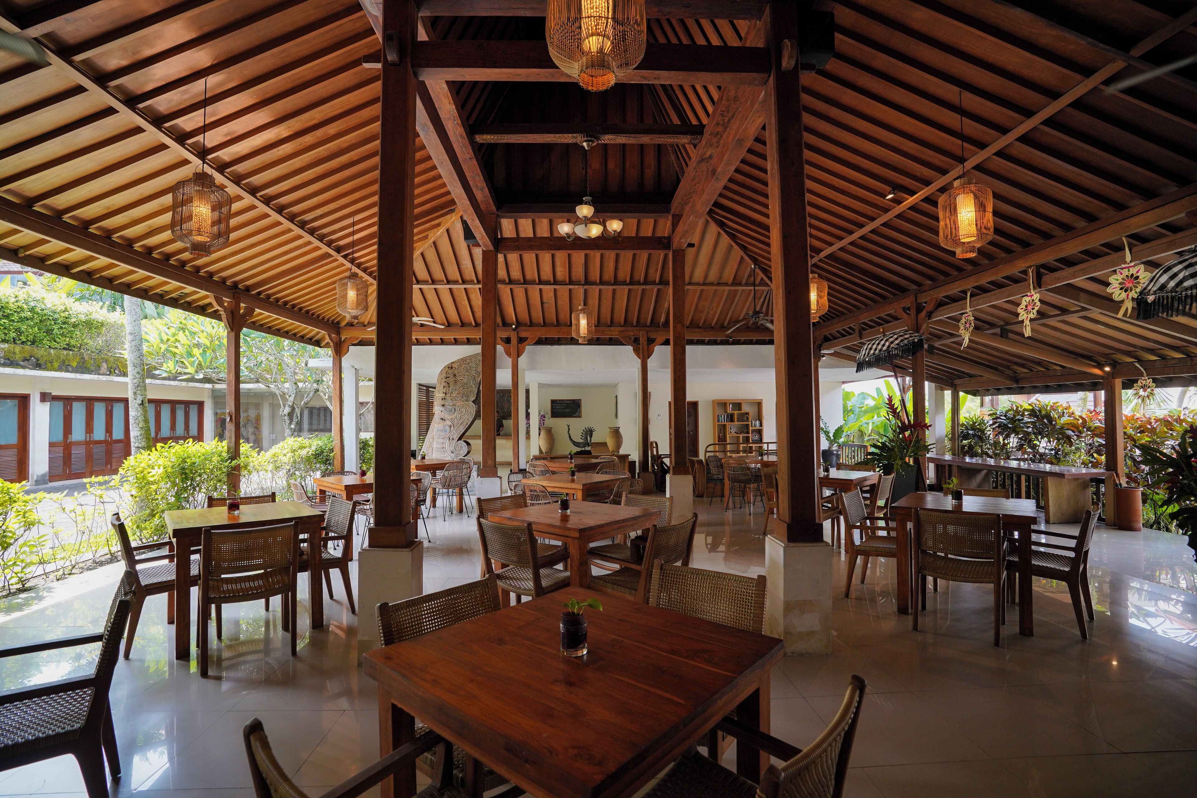 A spacious covered patio with wooden tables and chairs, a central dining table, and hanging lanterns.