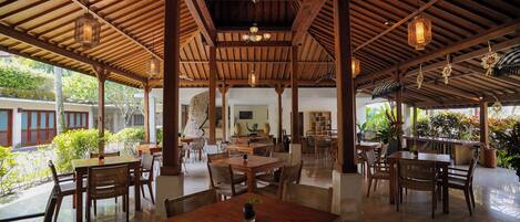 A spacious covered patio with wooden tables and chairs, a central dining table, and hanging lanterns.