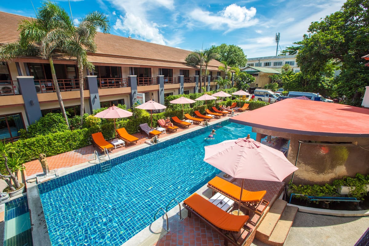A hotel with a swimming pool, sun loungers, and umbrellas.