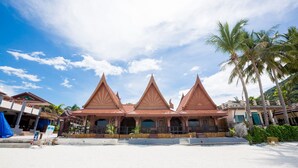 A traditional multi-tiered building with a symmetrical roof design, situated on a sandy beach with palm trees in the background. - Sunrise Resort (Ko Pha-ngan)
