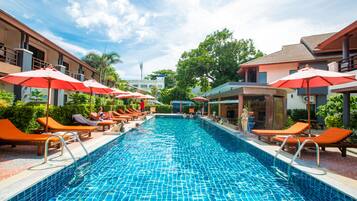 Una piscina al aire libre, sombrillas, sillones reclinables de piscina