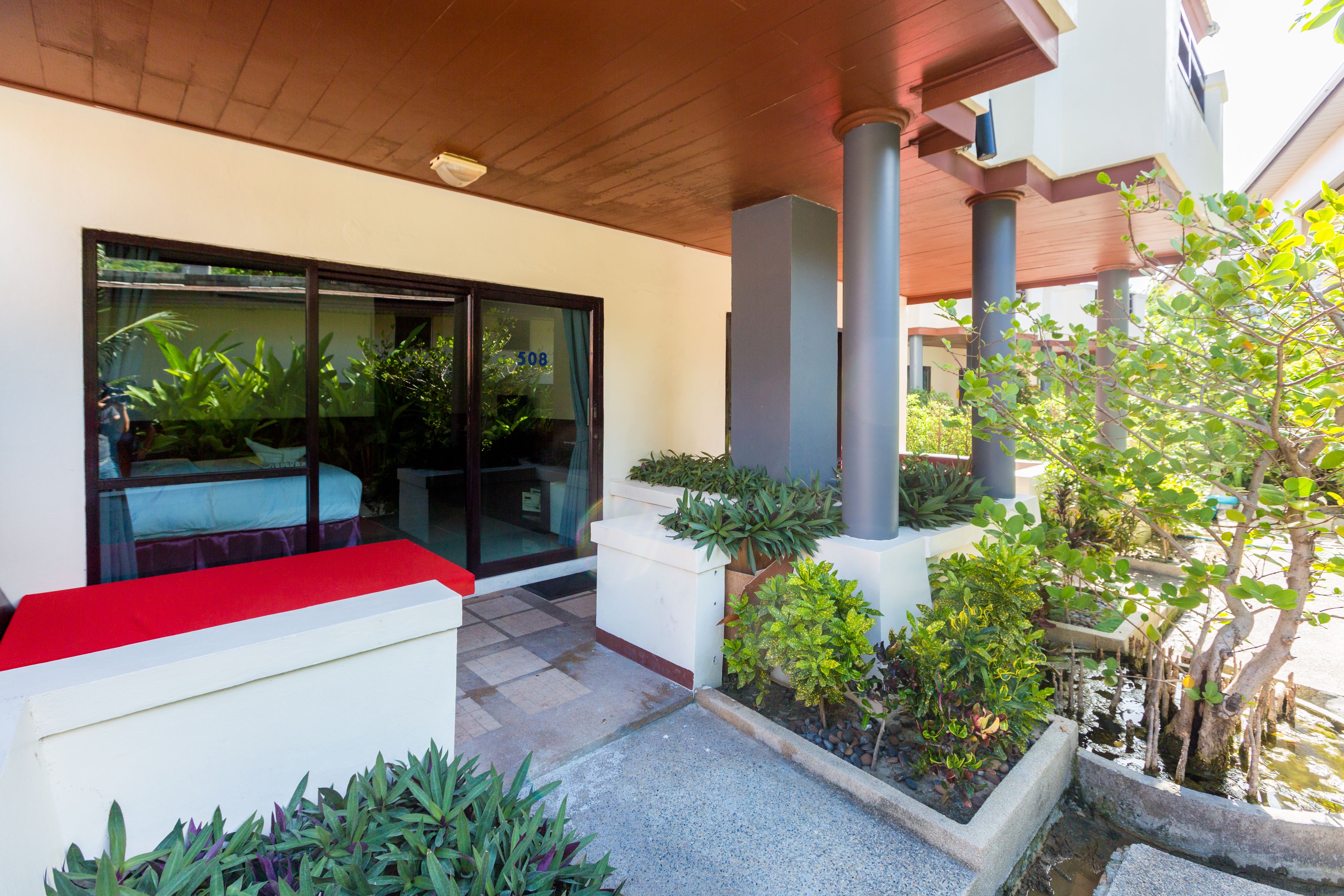 A modern building with a red bench, a glass door, and a small garden area with plants and a water feature.