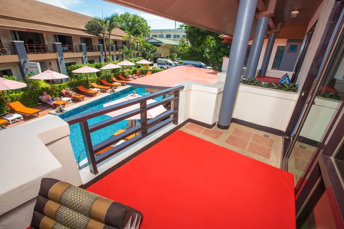 A hotel balcony with a pool, lounge chairs, and umbrellas.