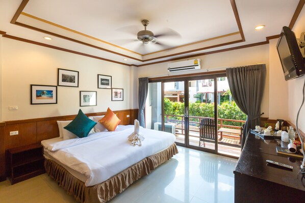 A hotel room with a bed, a TV, a desk, and a balcony with a view. - Sunrise Resort (Ko Pha-ngan)