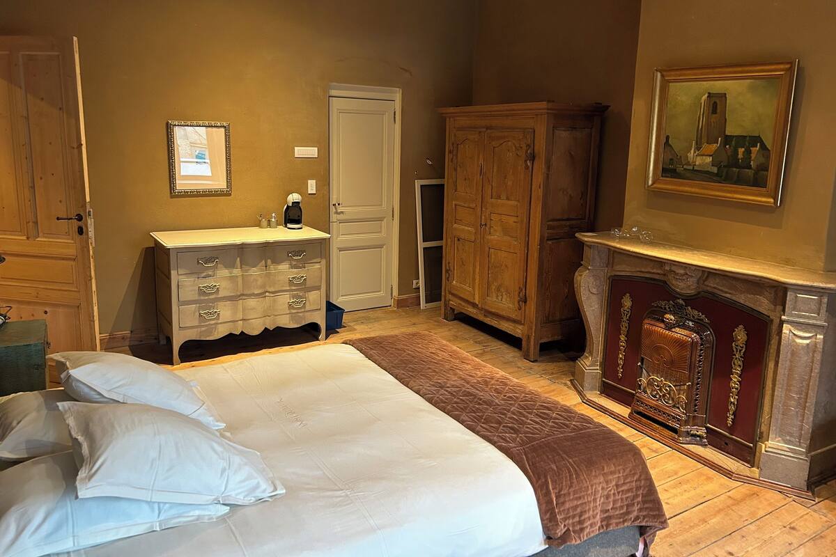 Une chambre à coucher comprenant un lit, une commode, une armoire et une cheminée.
