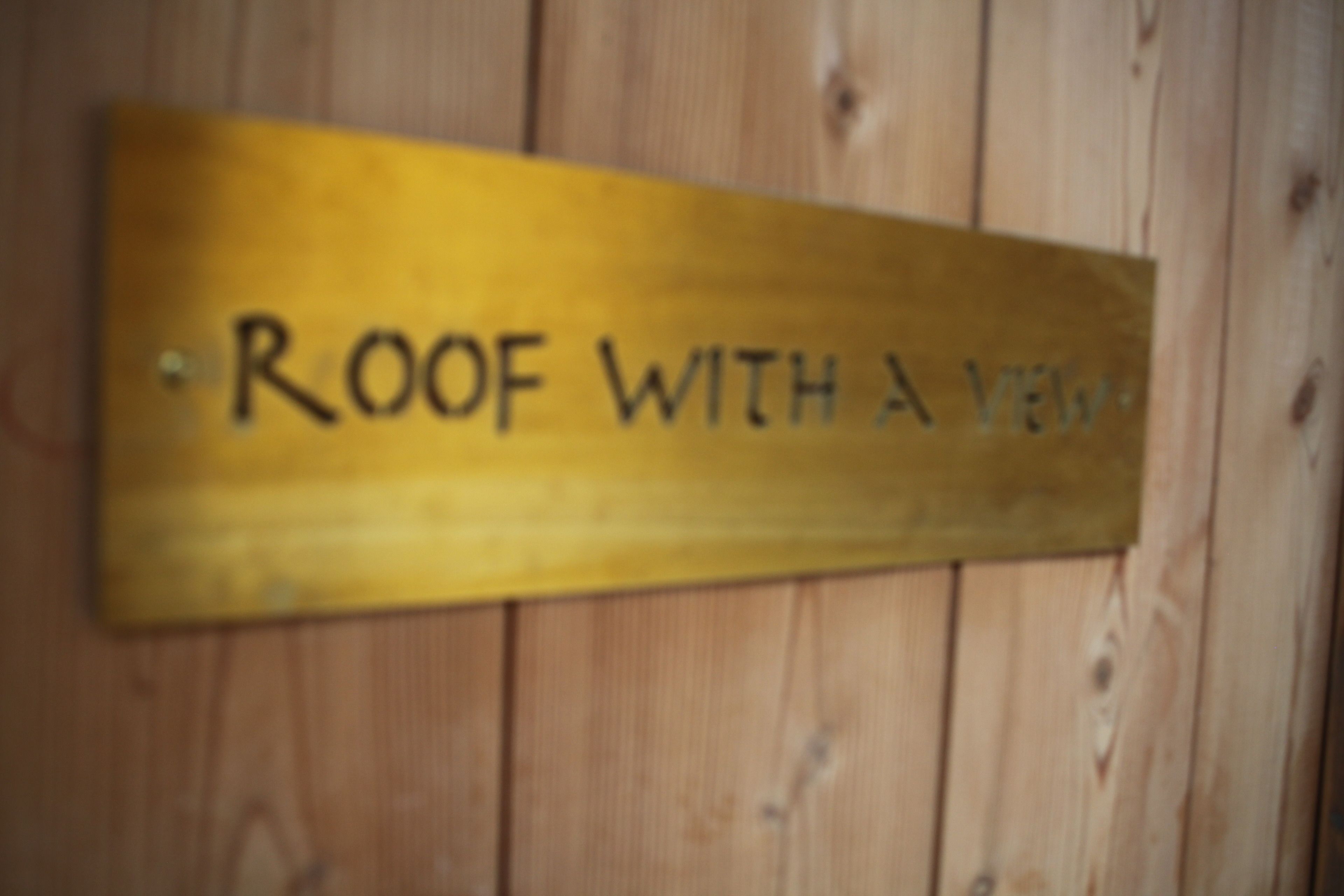A wooden sign with the text "ROOF WITH A VIEW".