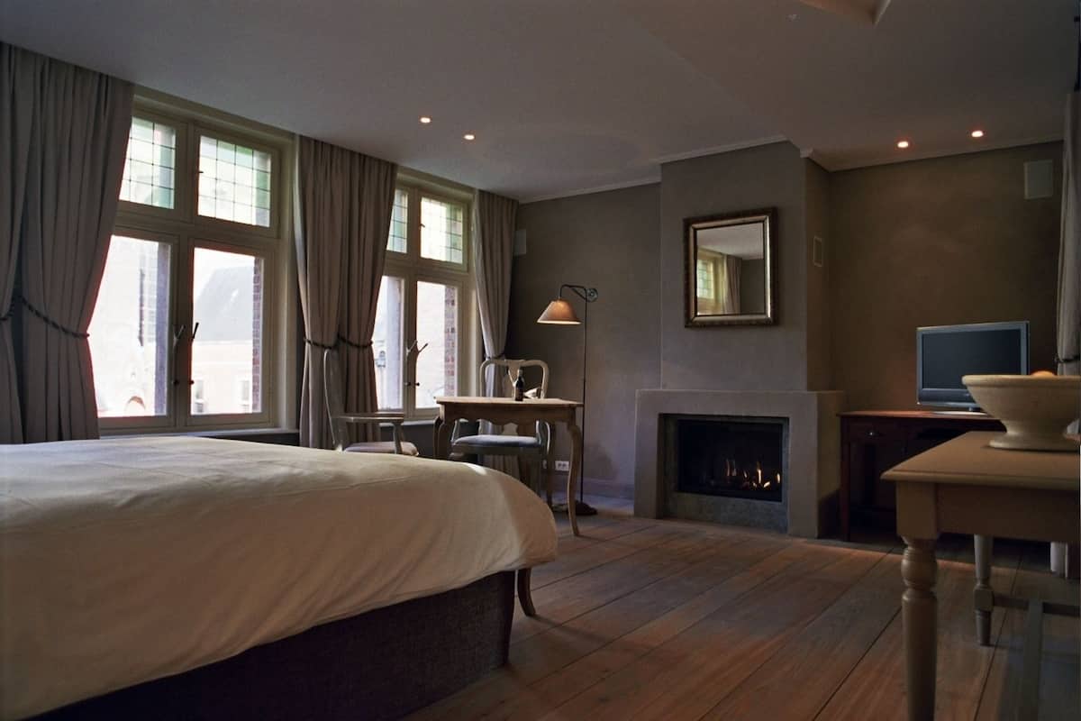 Une chambre d’hôtel avec un grand lit, une cheminée, une télévision et une table à manger.