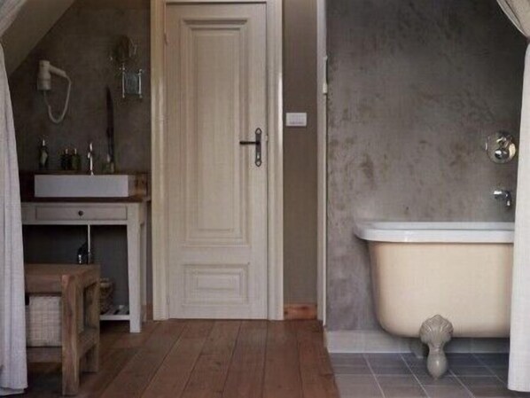 A bathroom with a white door, a bathtub, and a wooden bench.