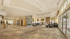 A spacious lobby with a reception desk, seating area, and large windows.