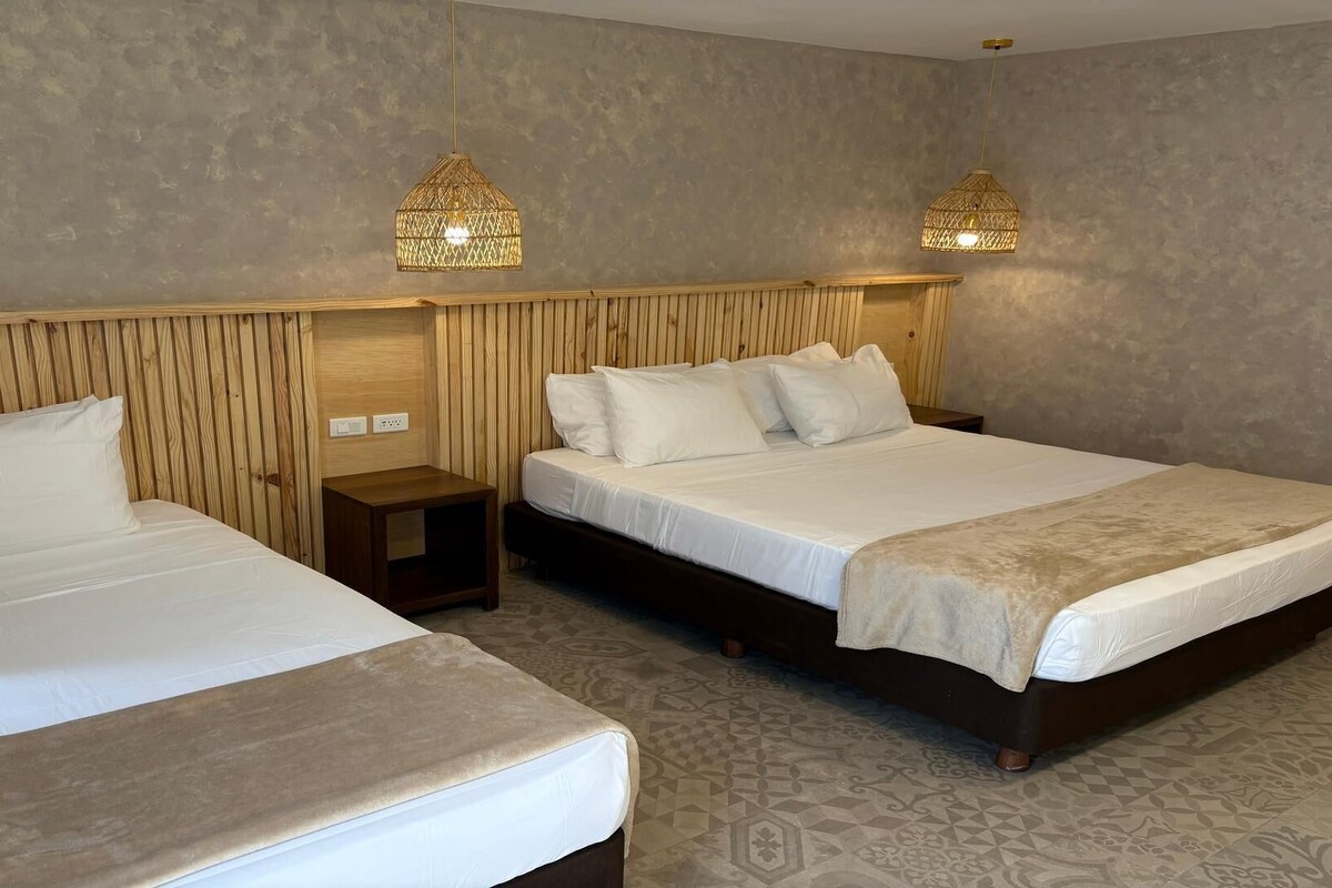 Una camera d'albergo con due letti, testiere in legno e due luci a parete.