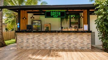 A bar with a neon sign reading 'GREEN HOUSE' and a counter with a wooden and stone tile backsplash.