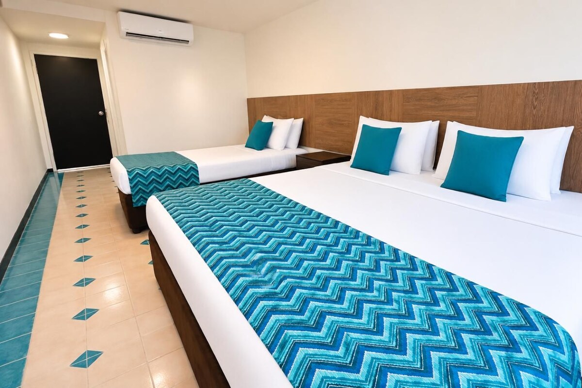 Une chambre d’hôtel avec deux lits, une tête de lit en bois et un sol à motifs.