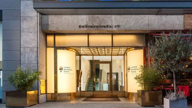 L'ingresso di un edificio con un cartello che recita 'Clipper Boarding House' e una scala che conduce all'interno.