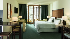 Una camera d'albergo con un letto, due sedie, una scrivania e una televisione.