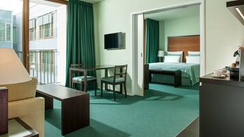 A hotel room with a bed, a desk, a chair, a TV, and a coffee machine.