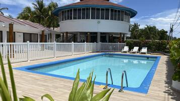 Una piscina al aire libre, sombrillas, sillones reclinables de piscina