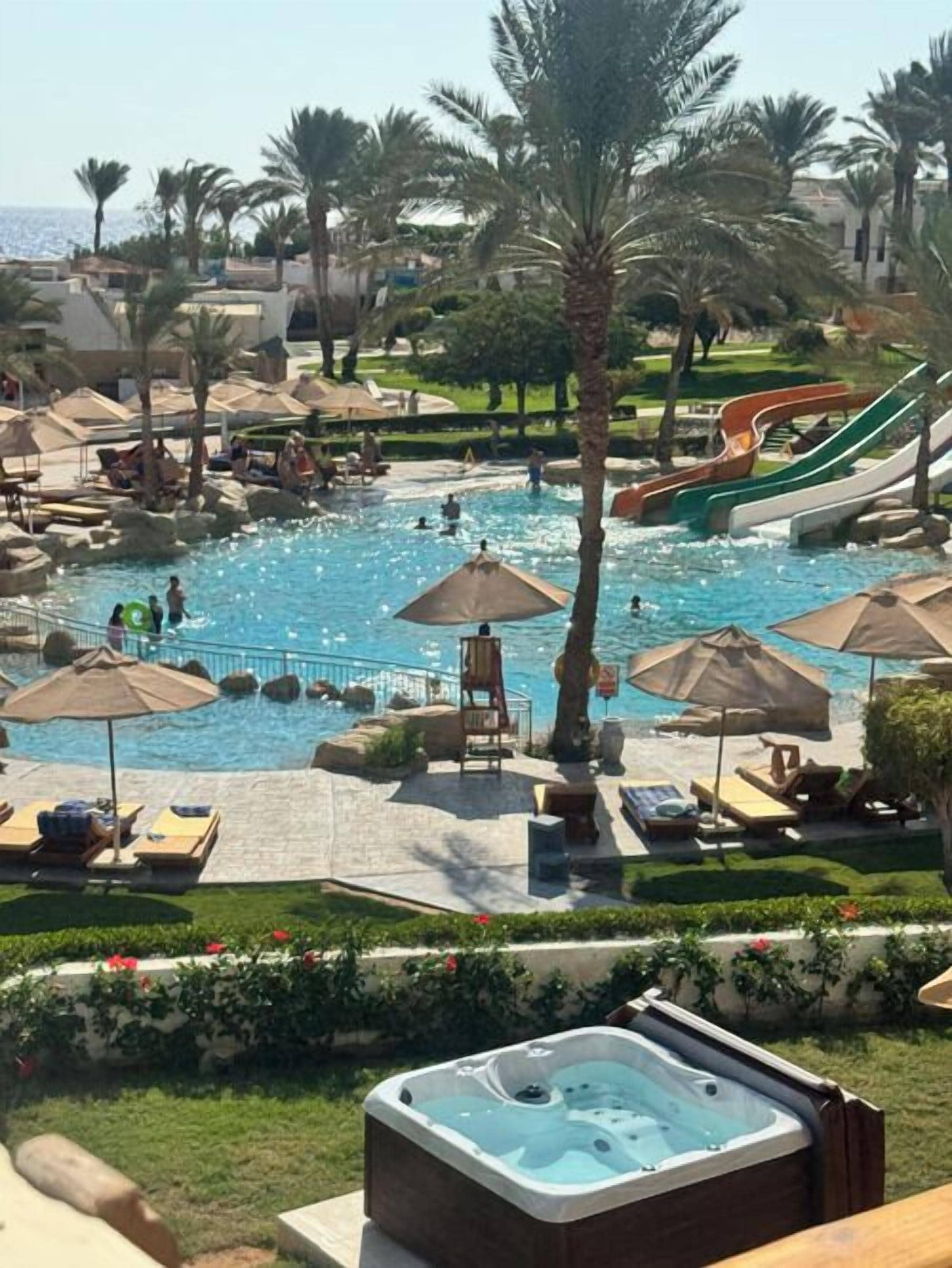 A resort pool area with slides, lounge chairs, and a hot tub.