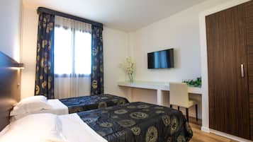 Ett hotellrum med två sängar, ett skrivbord med en stol, en TV och en garderob.
