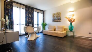 Un salon moderne avec un canapé, une table à manger et une chaise. On peut y voir une plante et un vase posés sur une table d’appoint.