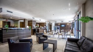 A modern lobby with a reception desk, seating area, and a dining space. - Matrix Hotel & Residence (Vigonza)