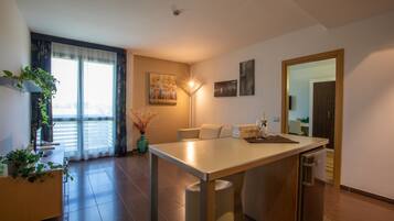 Een moderne keuken met een centraal eiland, een eethoek en uitzicht op de omgeving door grote ramen.