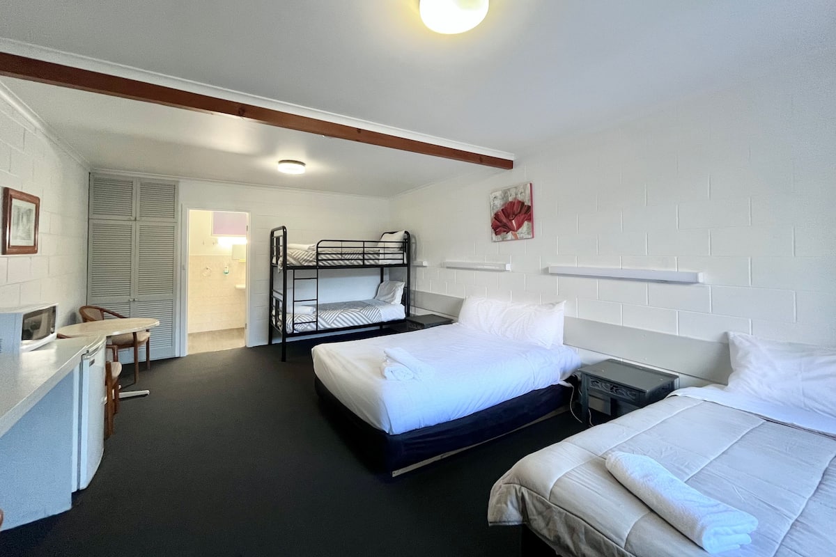 Et hotelværelse med køjesenge, et skrivebord med stol og et lille tekøkken.