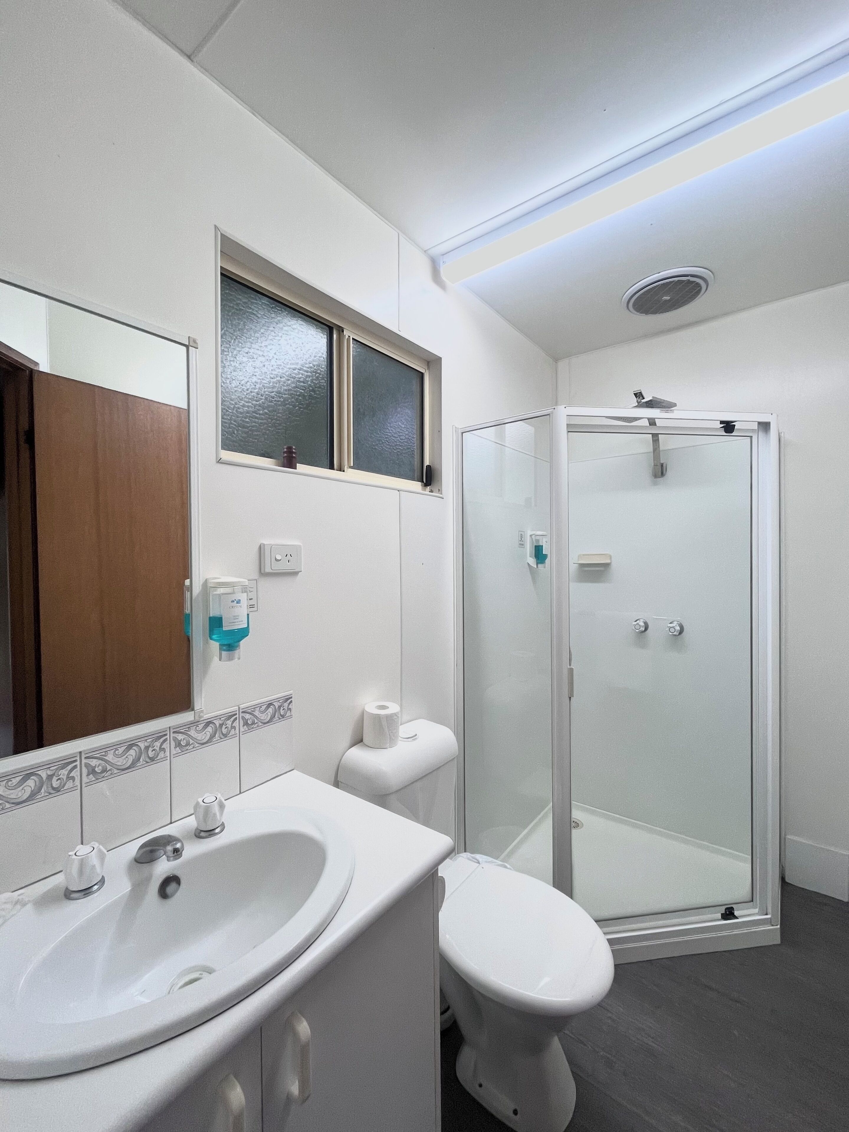 A bathroom with a white sink, toilet, and glass-enclosed shower.